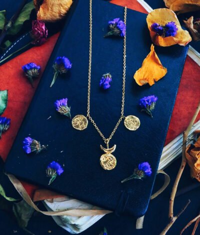 sun and moon gold necklace flat lay with flowers