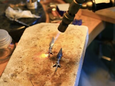 Soldering process at jewelry bench — artisan handcrafting Mandaya pendant with torch flame, forged in tradition.