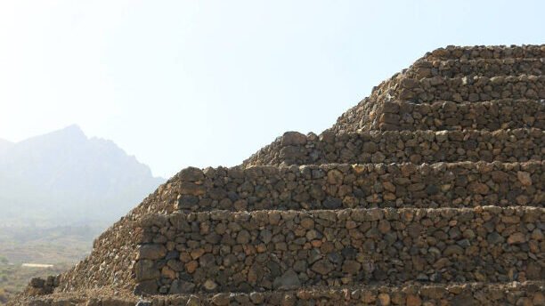 Guanche pyramids in Tenerife, Canary Islands, showcasing ancient stone structures against a backdrop of lush foliage and clear sky